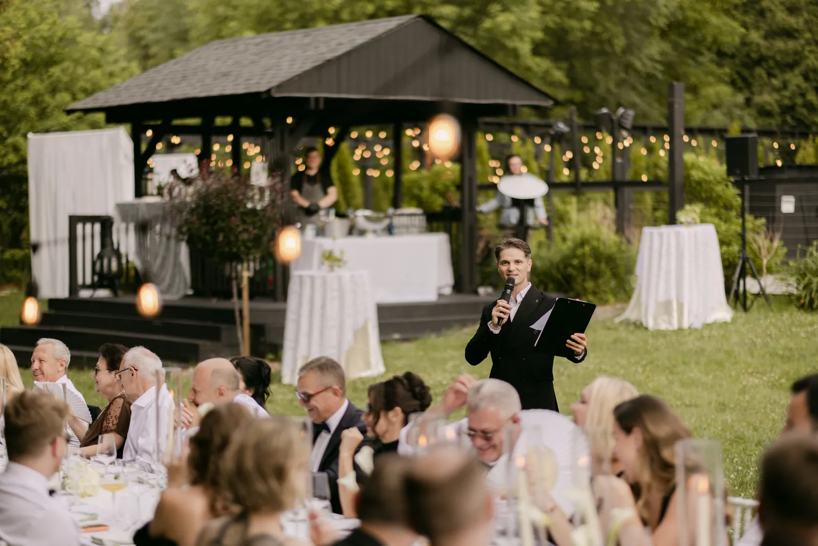 Vladyslav hosting an outdoor reception under string lights