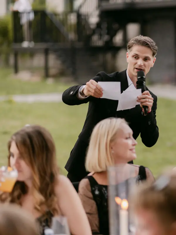 Vladyslav reading a card to the guests at the table