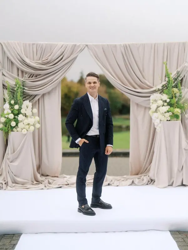 Vladyslav standing at a wedding ceremony arch