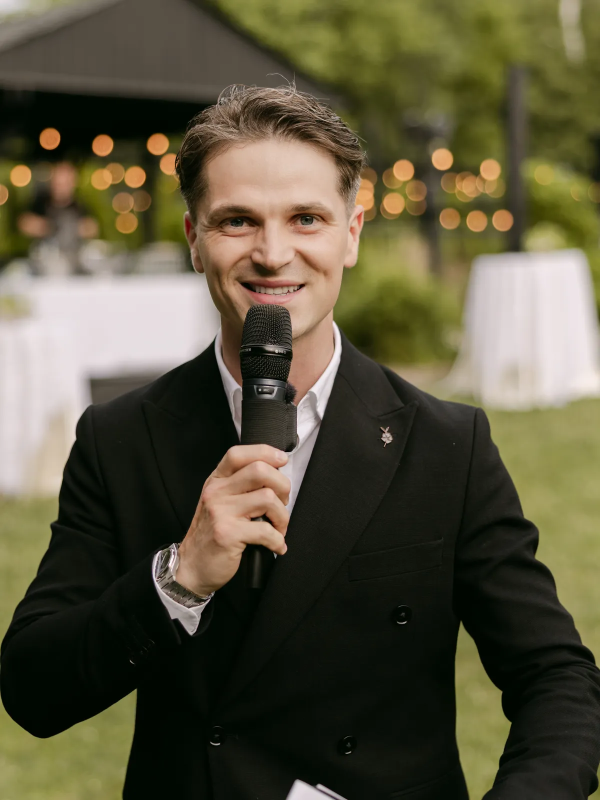 Vladyslav Katsalap hosting an outdoor wedding reception with a microphone