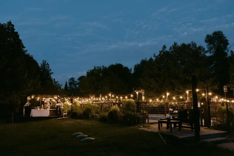 String lights over an outdoor reception at dusk